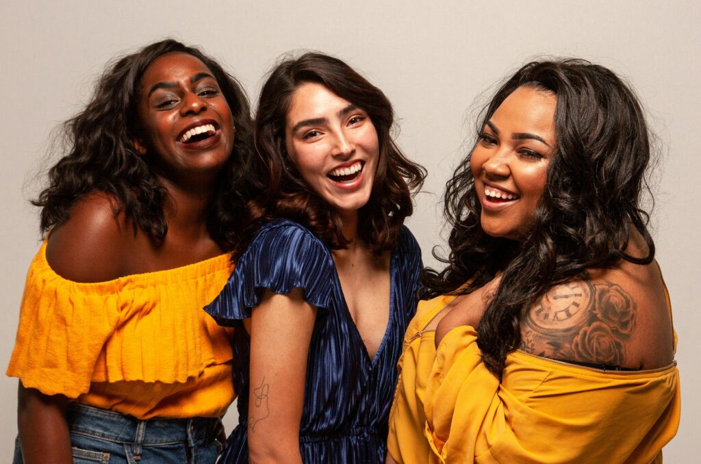 Joyful group of diverse women laughing together in bright outfits.