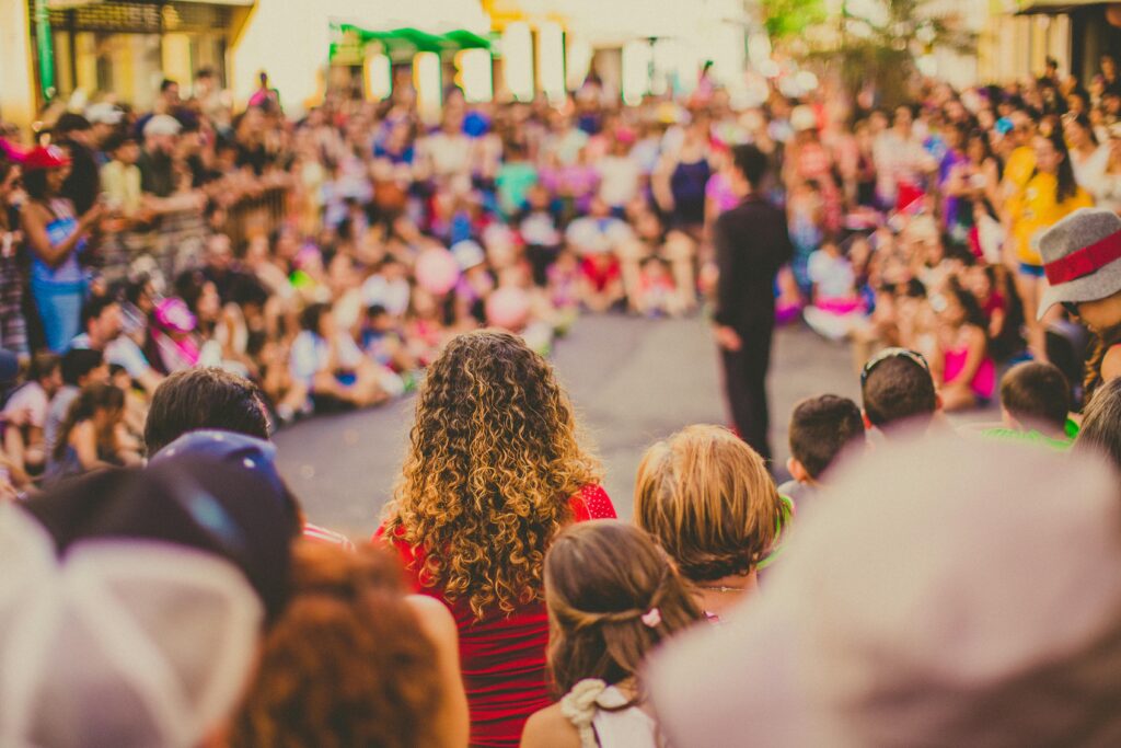 A lively street performance with a diverse and engaged audience enjoying the show.