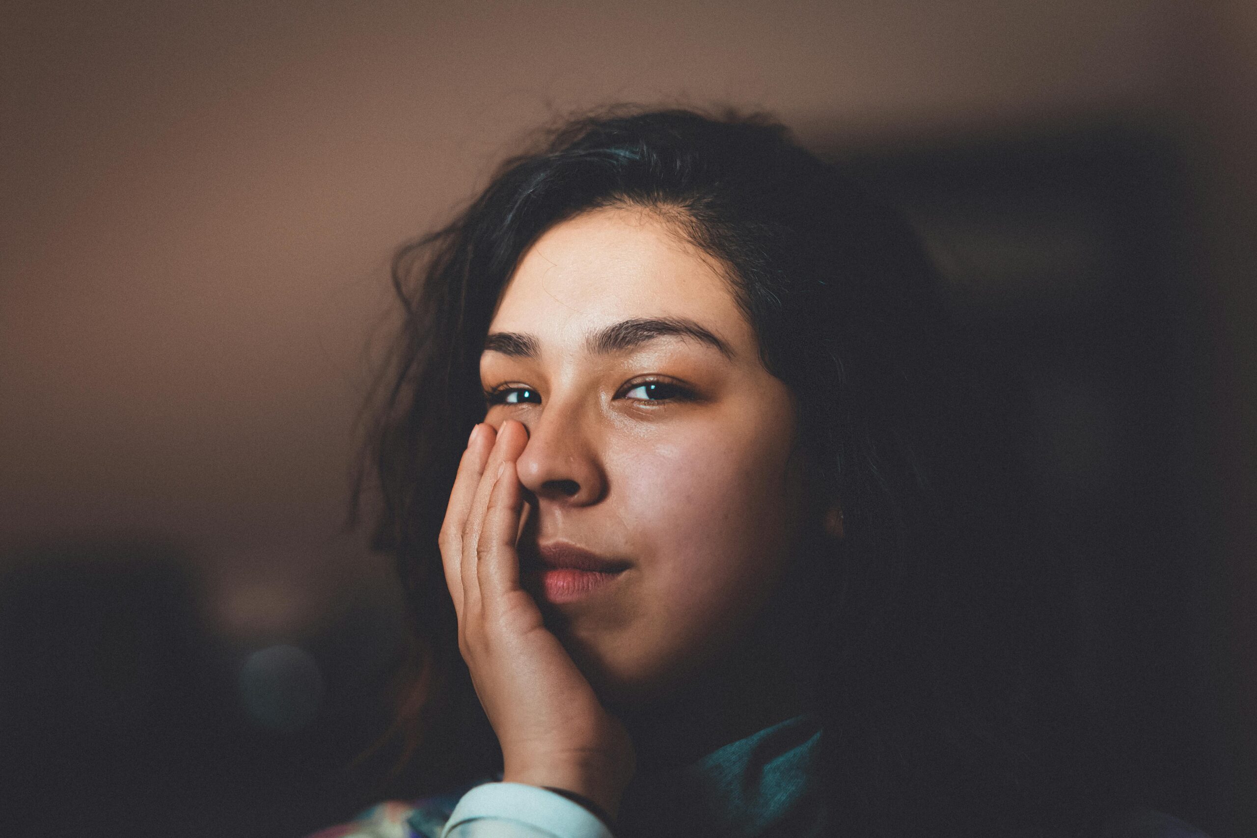 A serene close-up portrait of a woman indoors, highlighting natural beauty and expression.